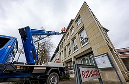 Unter dem Dach des Rathauses wird der neue Nistkasten für Mauersegler montiert.