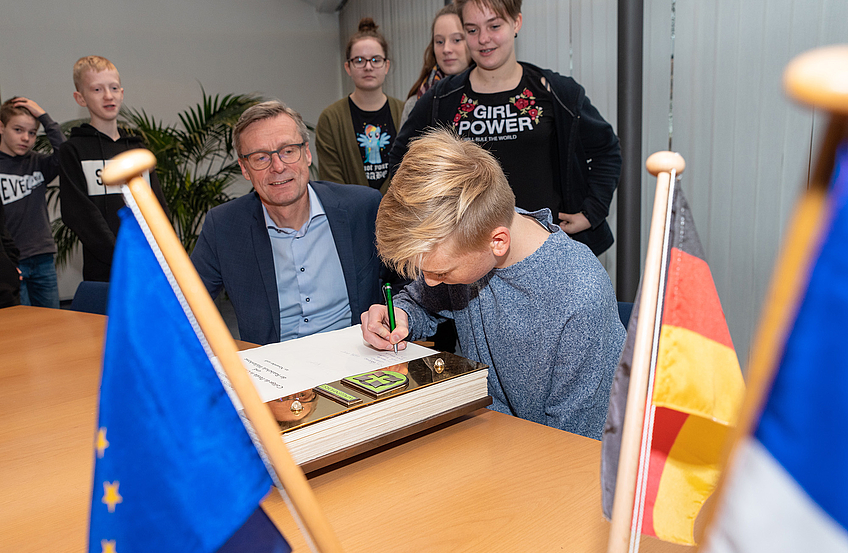 Die Schülerinnen und Schüler tragen sich im Beisein von Bürgermeister Otto Steinkamp ins Goldene Buch der Gemeinde Wallenhorst ein.