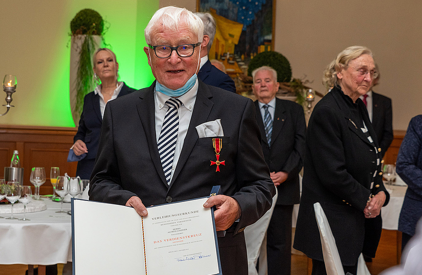 Alfred Lindner mit dem Bundesverdienstkreuz und der Urkunde des Bundespräsidenten.
