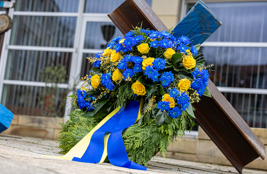 Ein Kranz in den ukrainischen Farben erinnert vor der Kunstinstallation „Gedankensperre“ an die Opfer des Krieges.