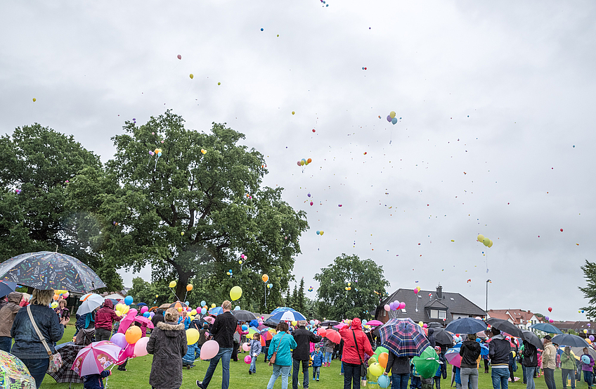 Über dem Sportplatz kämpfen die Ballons gegen den Regen an und bahnen sich langsam den Weg gen Himmel.