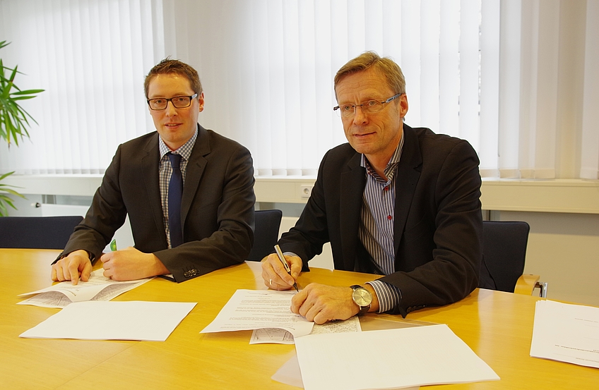 Komnexx-Geschäftsführer Silas Bittmann und Bürgermeister Otto Steinkamp (von links) unterzeichnen den Pachtvertrag für das Glasfasernetz der Gemeindewerke Wallenhorst.