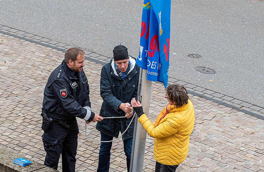 Christian Netsch, Rüdiger Mittmann (Fachbereichsleiter Bürgerservice und Soziales) und Kornelia Böert hissen die Fahne von „Terre des Femmes“ vor dem Rathaus.