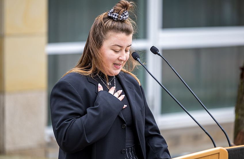 Anna Eberding verliest die Grußbotschaft des Künstlers Volker-Johannes Trieb.