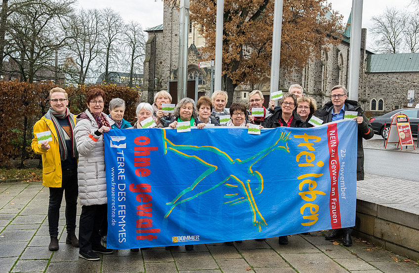 Ratsmitglieder und Vereinsvertreterinnen zeigen gemeinsam mit Bürgermeister Otto Steinkamp (rechts) und Kornelia Böert (4. von rechts) Flagge gegen Gewalt an Frauen.