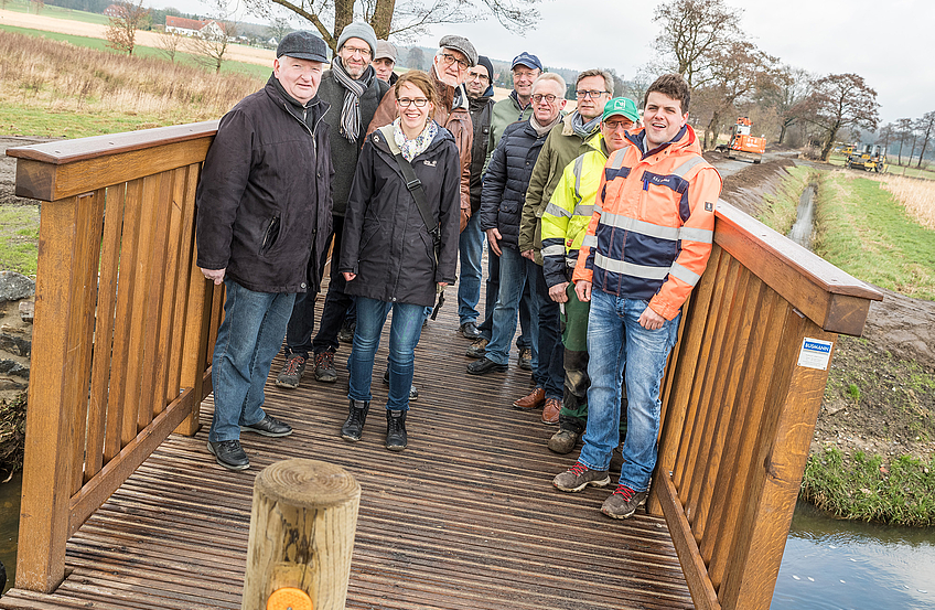 Mitglieder des Arbeitskreises Dorferneuerung, Vertreter der Gemeindeverwaltung und der Baufirmen sowie Bürgermeister Otto Steinkamp (3. von rechts) präsentieren die neue Brücke am Erftenbecksweg.